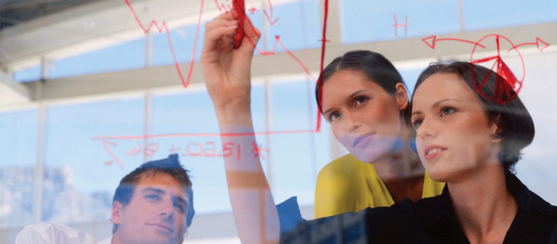 Mujeres de negocios dibujando gráficos sobre vidrio