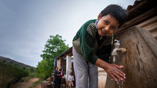 Niño utilizando una fuente de agua potable