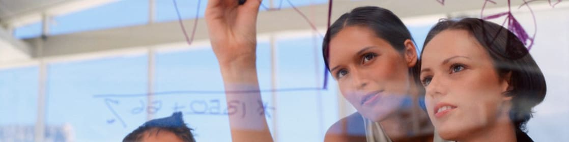 Mujeres de negocios dibujando gráficos sobre vidrio